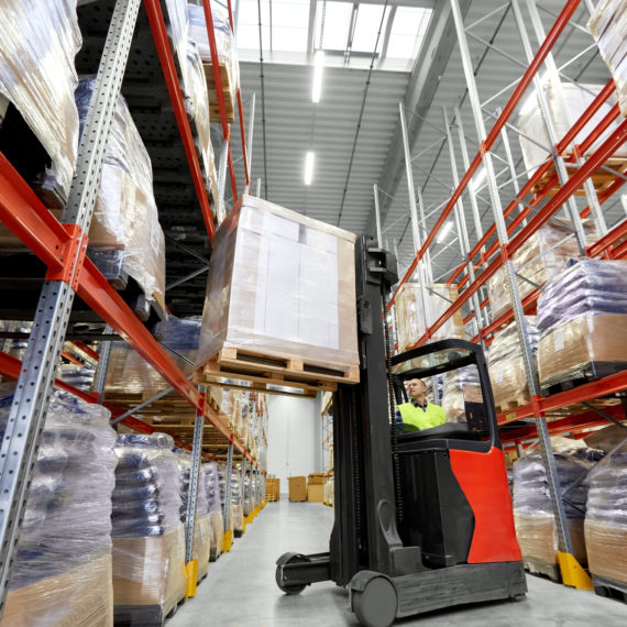 logistic business, shipment and loading concept - loader operating forklift with cargo at warehouse